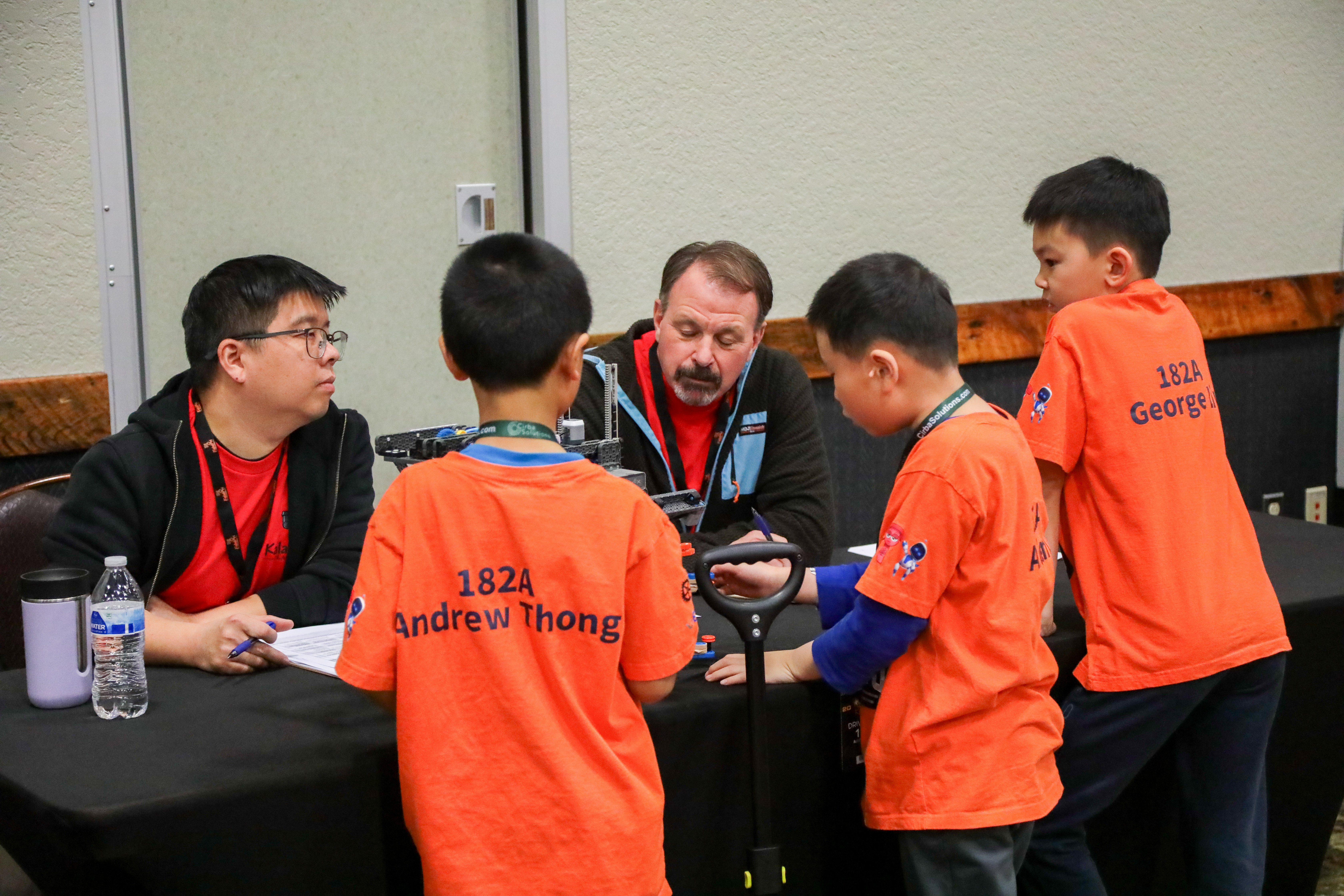 A table with two judges talks with a team, writing down notes as they converse.