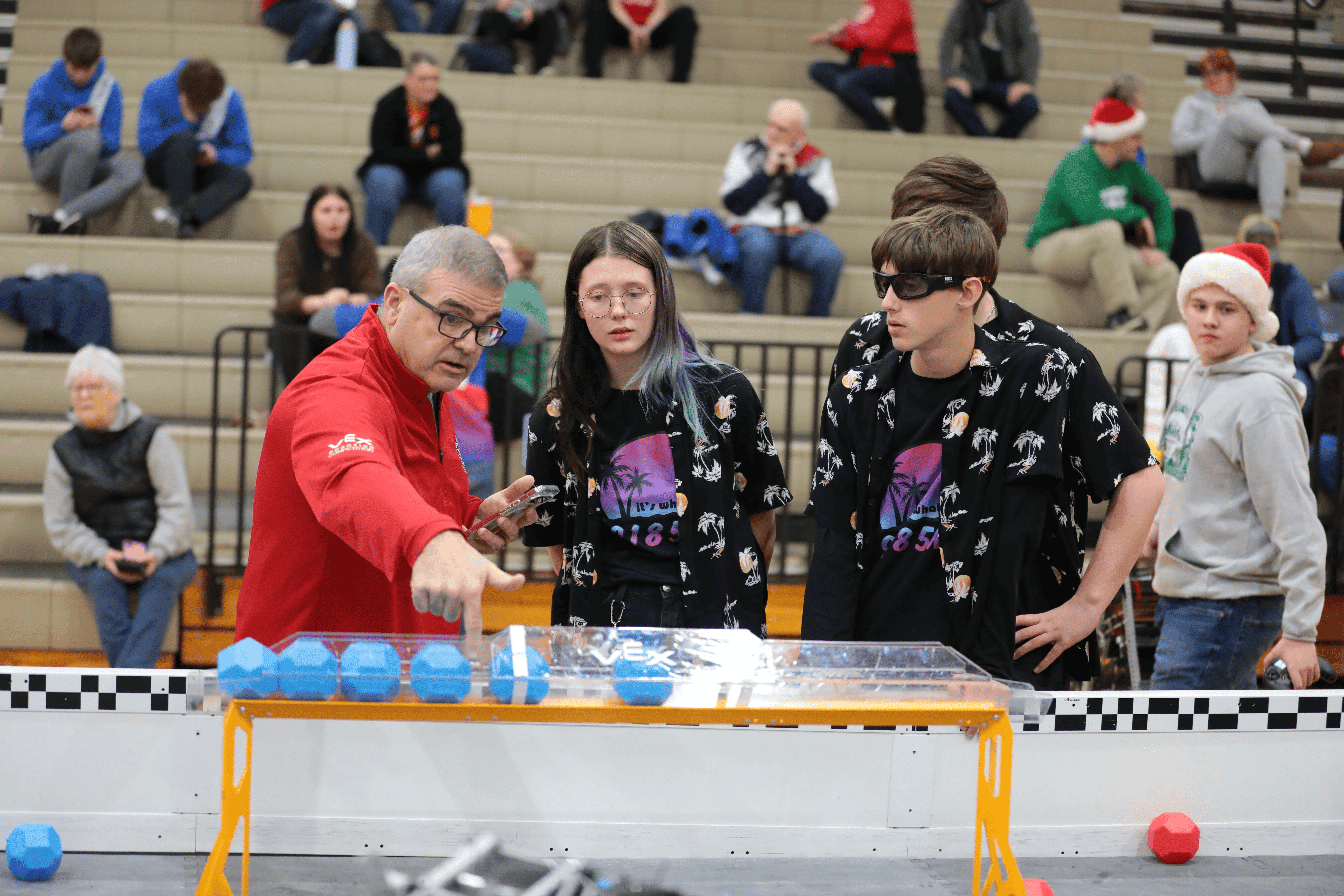 A judge points at a field element during an event and talks with three team members.