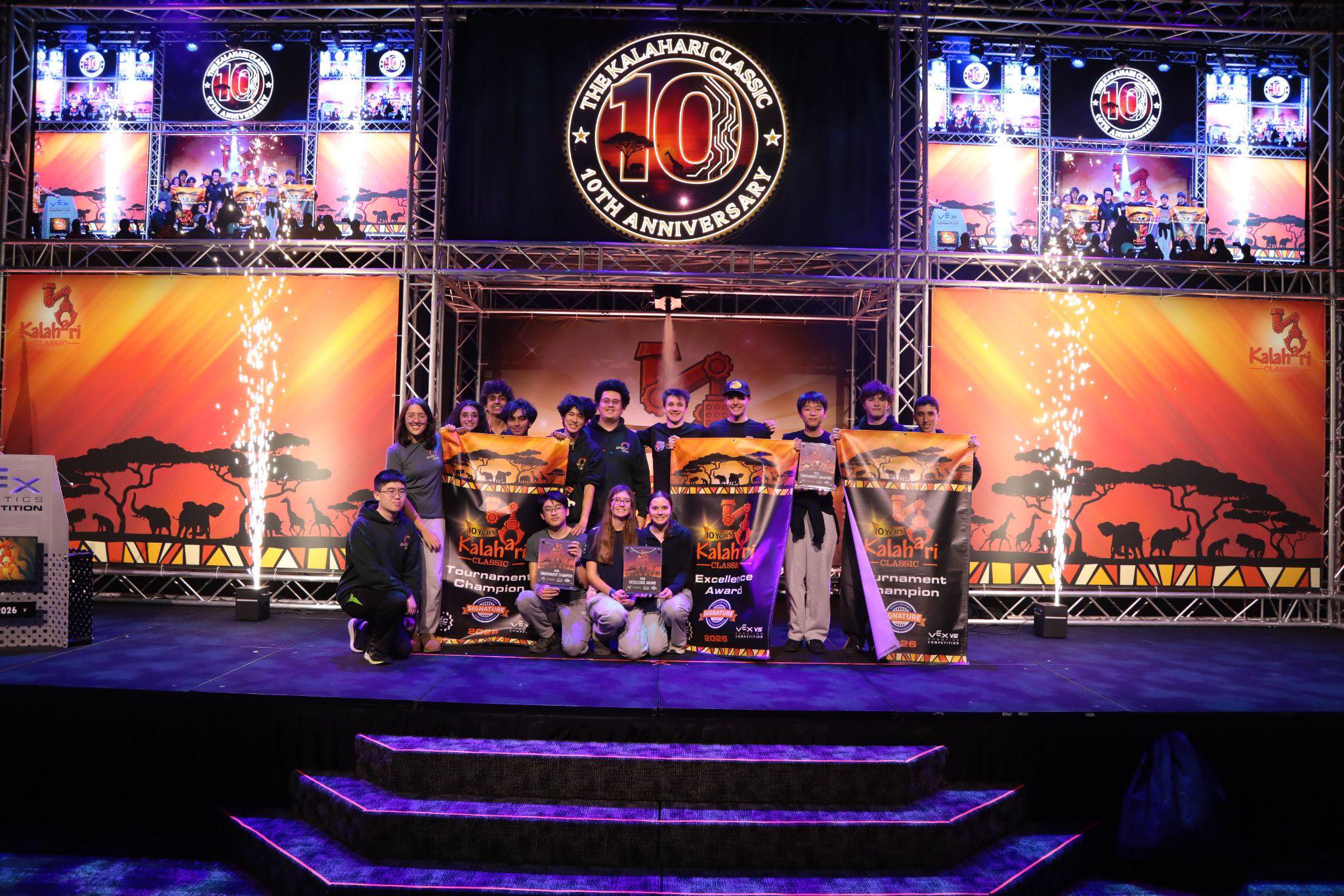 Teams celebrate with award banners on stage at a large-scale VEX Robotics event.