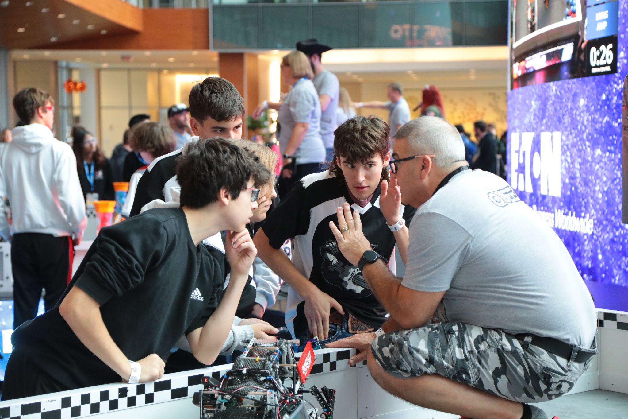 A Head Referee talks with team members at the edge of a competition field.