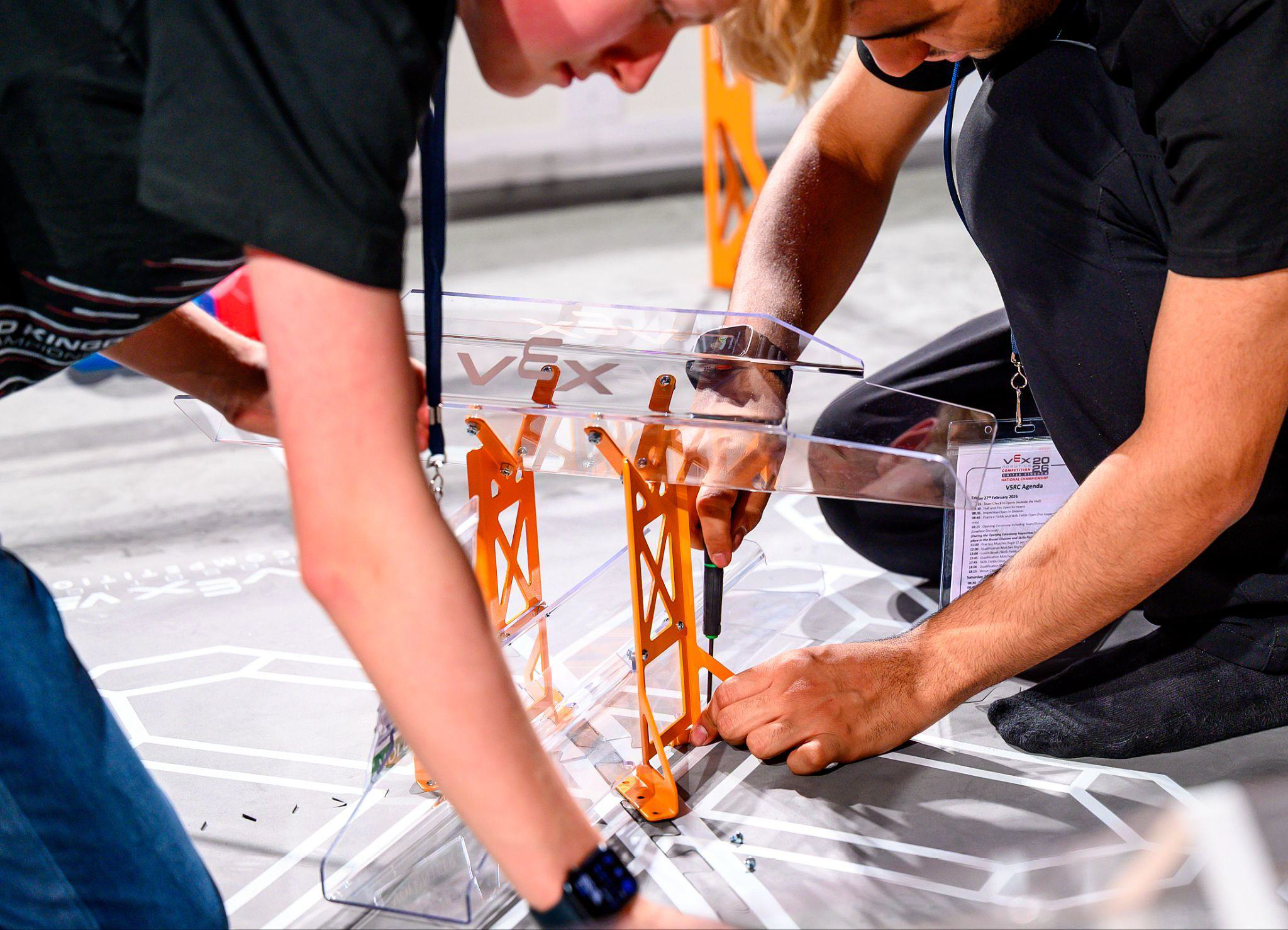 Two volunteers position game elements while setting up a competition field.