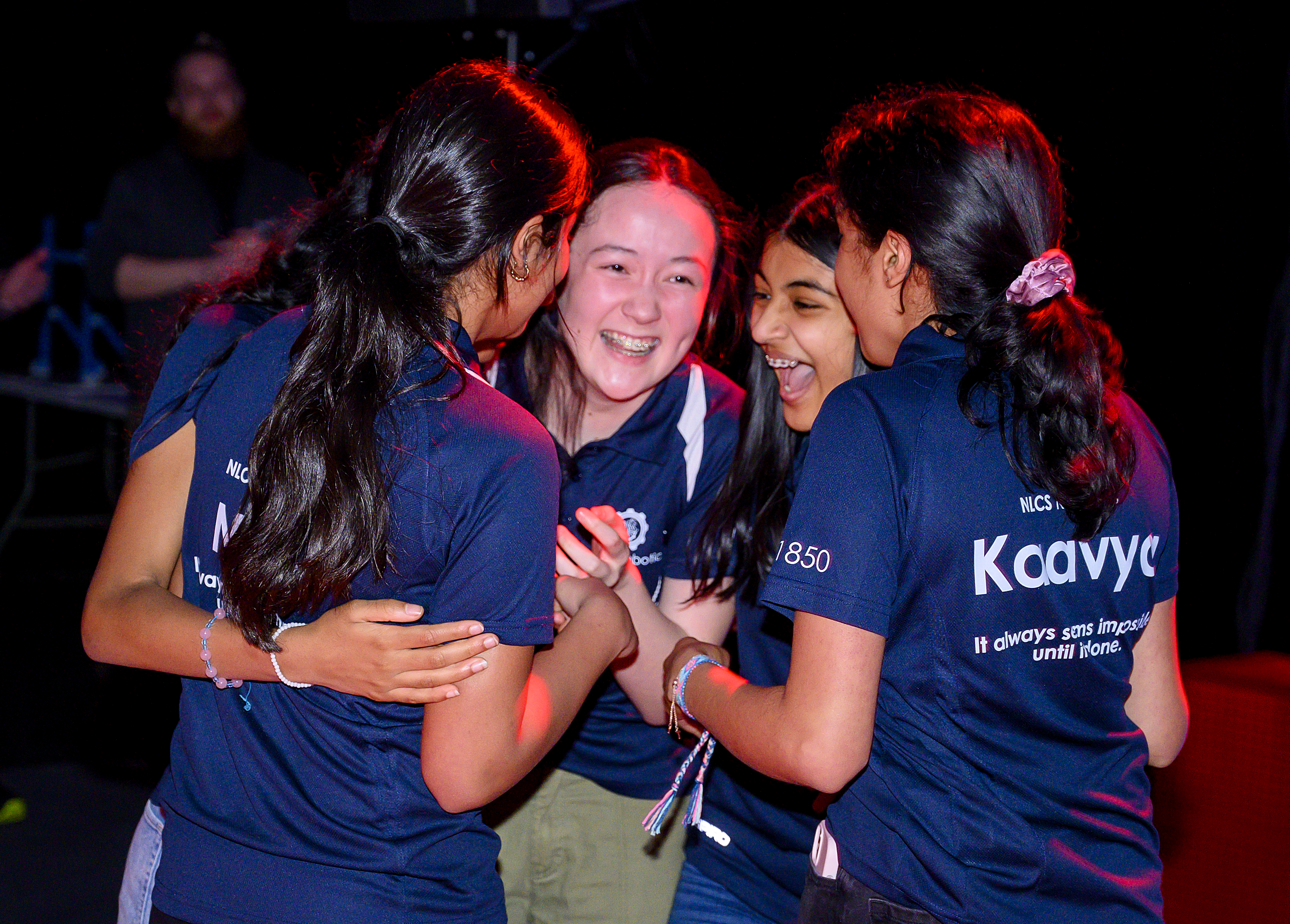 A team of robotics students celebrates together.